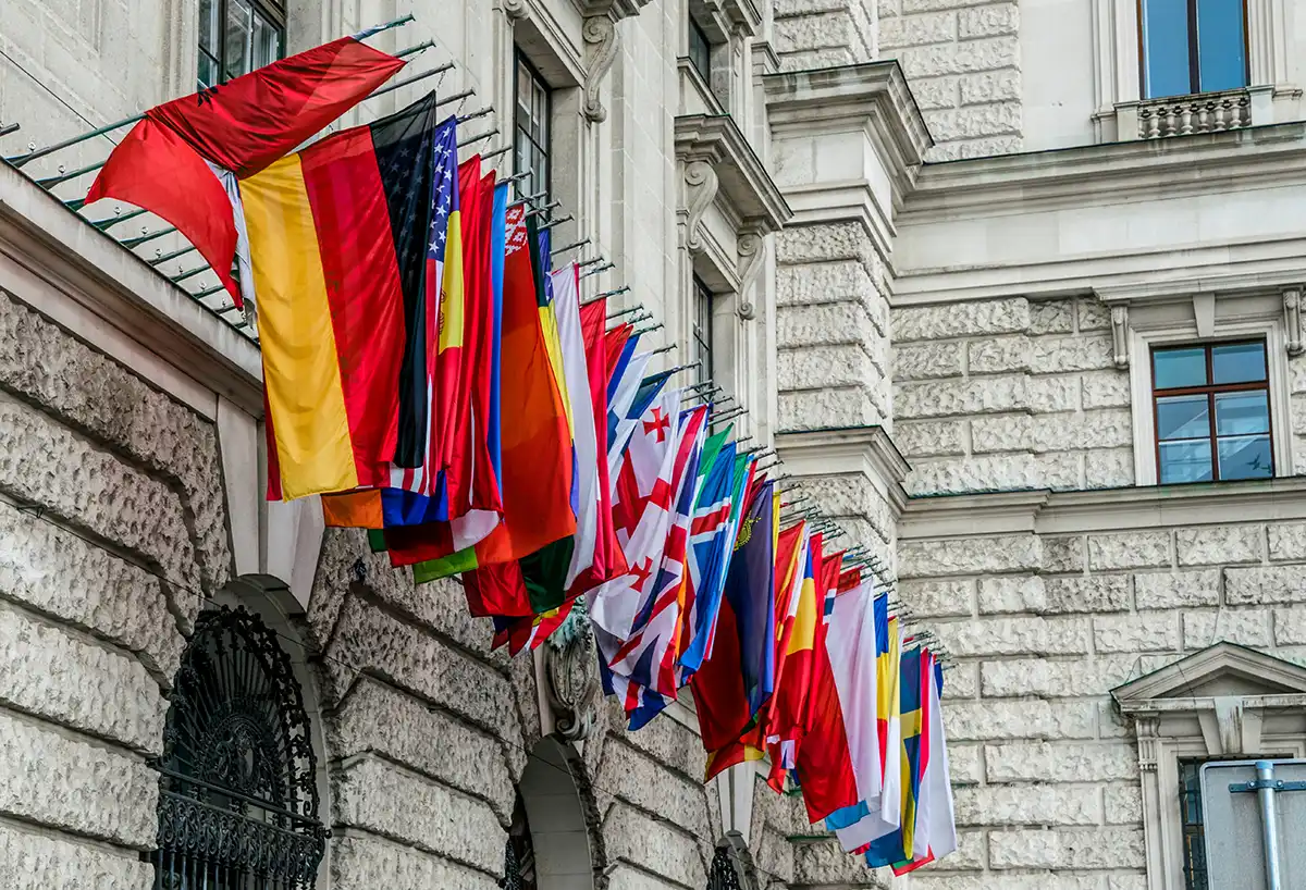 Reihe von Nationalflaggen an der Fassade eines diplomatischen Gebäudes als Symbol für die internationalen Vertretungen, die ein Aussenministerium weltweit unterhält.