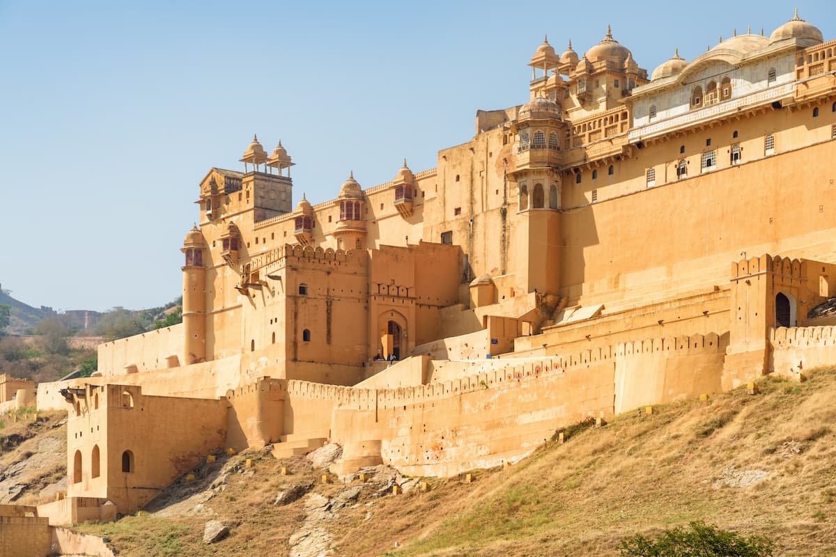 Amer Fort über dem Maota-See bei Jaipur in Rajasthan — Sandsteinmauern, terrassenförmige Innenhöfe und die umliegenden Aravalli-Höhenzüge.